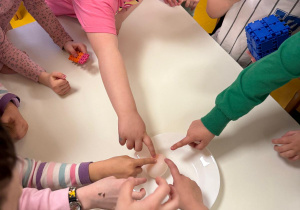 Dzieci sprawdzają co stało się z jajkiem zanurzonym w occie po kilku dniach.