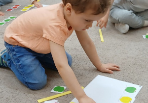 13.Chłopiec układa rytmy z jabłuszek.