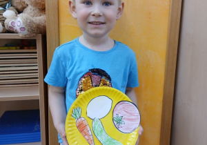 24. Chłopiec trzyma pracę plastyczną.