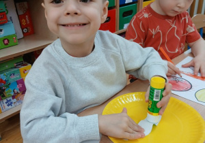 25. Chłopiec przykleja na talerz warzywa.