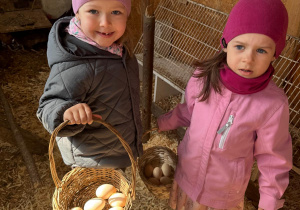 Dziewczynki pozują do zdjęcia z koszyczkiem z jajkami.
