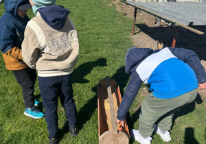 Dzieci wsypują ziarno dla kur.