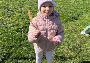 Dziewczynka trzyma w ręku znalezione piórko.