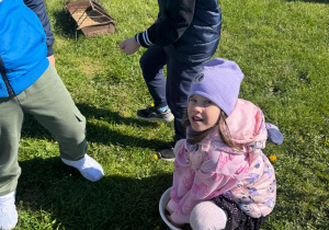 Dziewczynka nabiera w ręce ziarno dla kur.