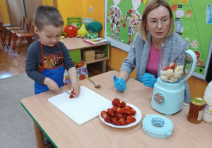 21. Chłopiec kroi truskawkę