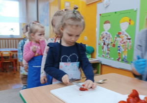 22. Dziewczynka kroi truskawkę