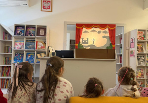 Dzieci oglądają w bibliotece teatrzyk kukiełkowy.