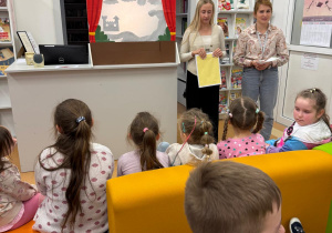 Dzieci oglądają w bibliotece teatrzyk kukiełkowy.