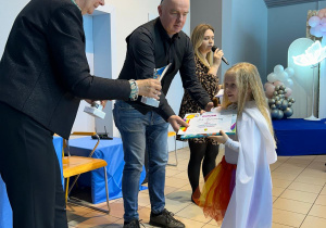 Dziewczynka odbiera dyplom i nagrodę.