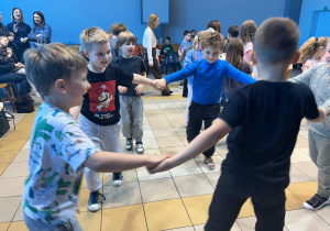 Dzieci tańczą trzymając się za ręce.