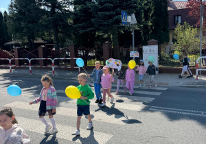 Dzieci maszerują z plakatami promującymi czytelnictwo.