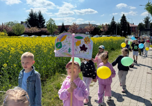 Dzieci idą na spacer podczas, którego promują czytelnictwo.