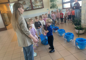 Przedszkolaki biorą udział w zabawie w której segregują śmieci.