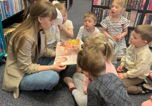 Pani bibliotekarka czyta dzieciom książkę pt. ,,Basia i śmieci".