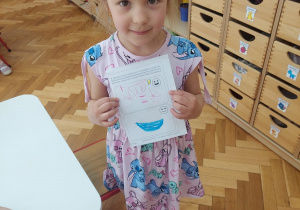 Dziewczynka prezentuje co sama narysowała.
