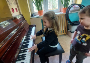 Dziewczynka dotyka klawiszy pianina.