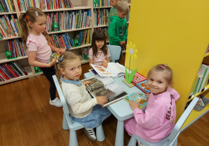 Dziewczynki siedzą przy stoliku i oglądają książki