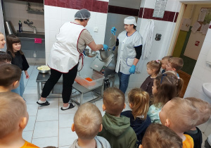 Panie kucharki wkładają do maszyny składniki na surówkę