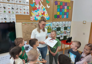 Przedszkolaki wręczają czytającej mamie podziękowanie