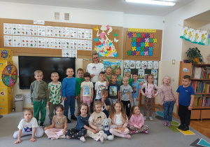 Przedszkolaki pozują z czytającym rodzicem do wspólnego zdjęcia
