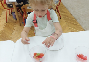 Dziewczynka komponuje deser z ulubionych owoców.