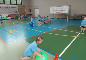 Kropelki wykonują ćwiczenia na hali sportowej.