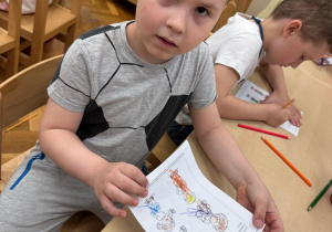 Chłopiec pokazuje wykonaną przez siebie pracę.