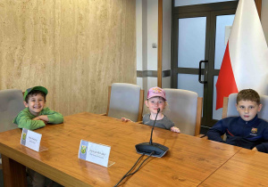 Dzieci siedzą w sali konferencyjnej.