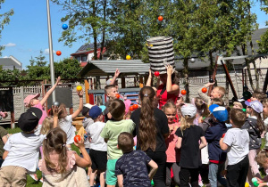 Dzieci podrzucają kolorowe kulki.