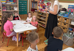 Pani Iza rozdaje dzieciom niezbędne akcesoria do pracy.