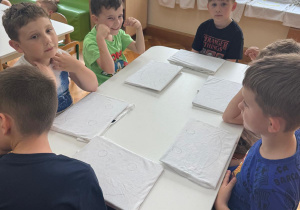 Dzieci słuchają w jaki sposób wykonać własną koszulkę.
