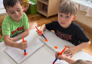 Dzieci malują farbami uśmiechnięte buźki.