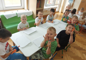 Dzieci siedzą przy stoliku i czekają na rozpoczęcie warsztatów