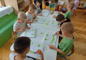 chłopcy malują oczy i uśmiech na swoich koszulkach