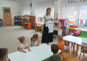 Pani Iza pokazuje dzieciom koszulki z imionami.