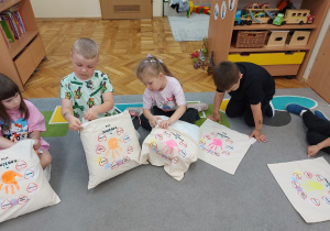 Przedszkolaki wkładają wkład do poszewek.
