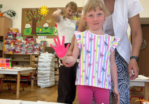 Dziewczynka prezentuje rączkę pomalowaną farbą.
