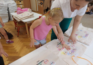 Dziewczynka odbija swoją dłoń na poduszce.