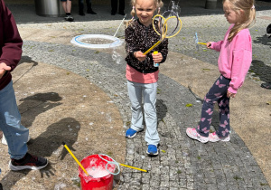 Dzieci puszczają duże bańki mydlane.