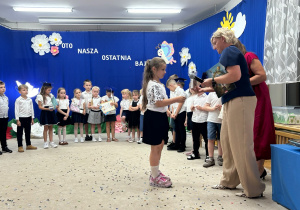 Pani dyrektor wręcza dziewczynce nagrodę.