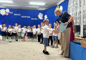 Pani dyrektor gratuluje chłopcu.