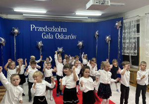 5 latki tańczą przed całą społecznością przedszkolną.