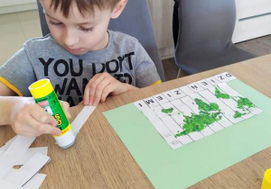 Przedszkolak przykleja puzzle literkowe