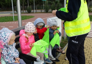 Pani Policjantka wręcza przedszkolakom odblaskowe chustki