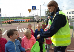Pani Marta rozdaję dzieciom chusty odblaskowe