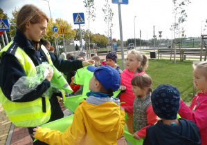 Przedszkolaki odbieraja chusty odblaskowe