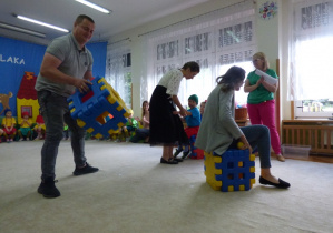 Rodzice układaja kostkę z klocków