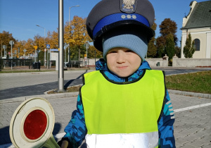 Chłopiec w policyjnej czapce i z tarczą do kierowania ruchem drogowym