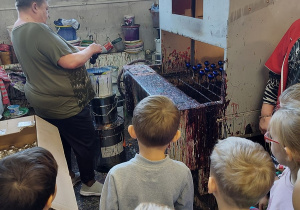 11. Pani pokazuje dzieciom jak wyglada proces malowania bombki farba.