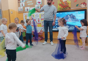 Maluszki poruszają kolorowymi chustkami w rytm muzyki.